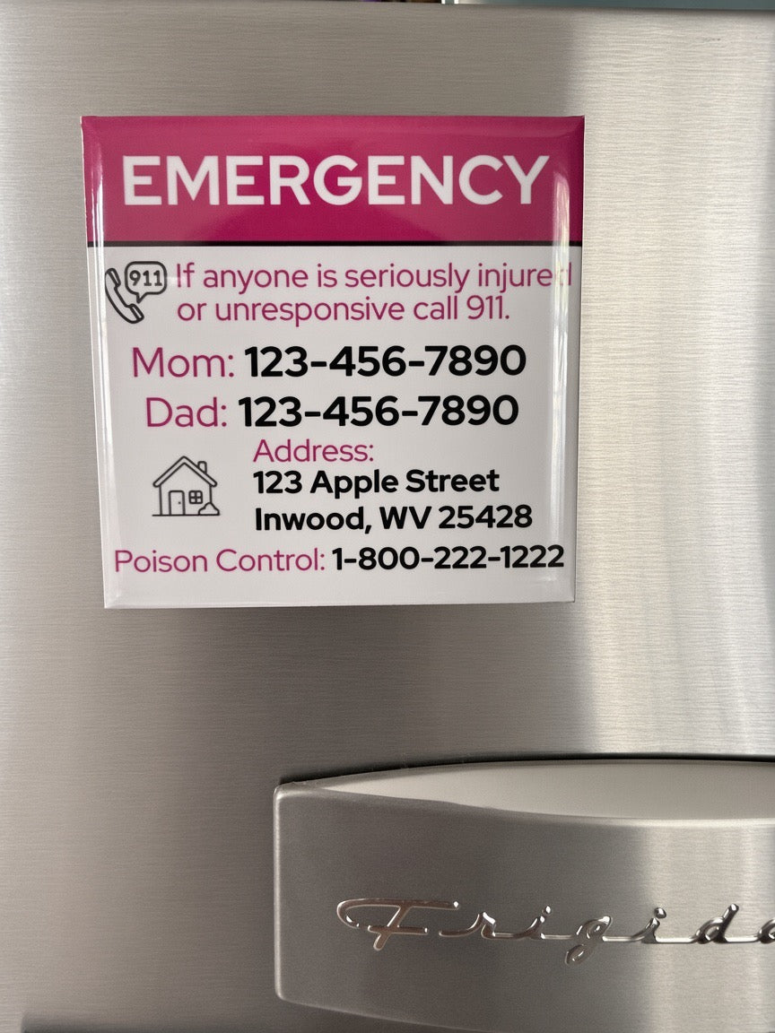 A refrigerator door with a printed emergency contact card attached. The card has a pink header reading 'EMERGENCY' and white background with black and pink text listing Mom's phone, Dad's phone, an address, and Poison Control.